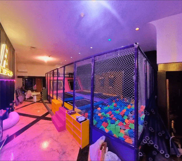 Connected trampoline beds with purple and yellow padding inside the netted enclosure.